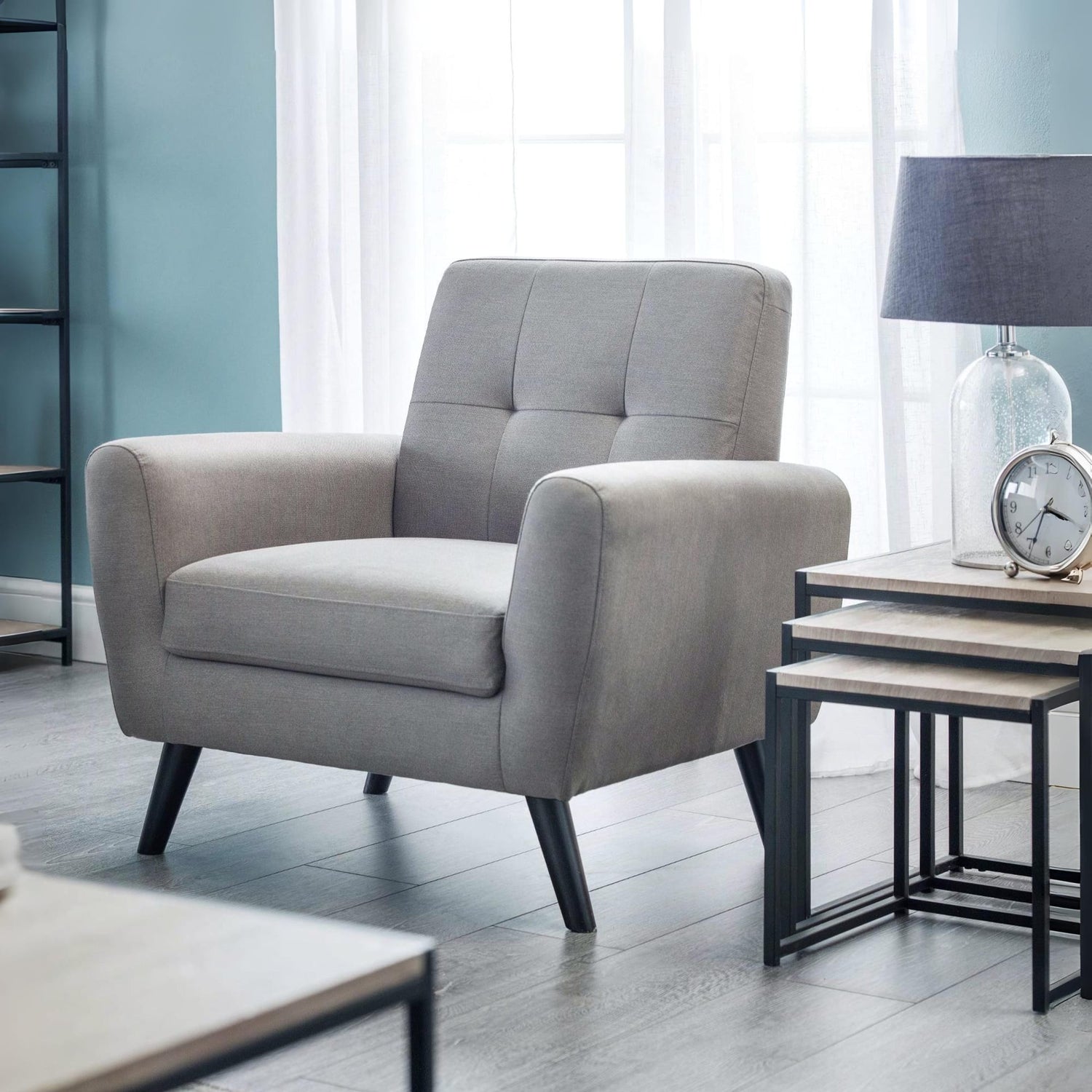 Gray armchair in a modern living room with side tables and decor.