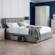 Gray upholstered bed with white bedding in a bedroom setting.