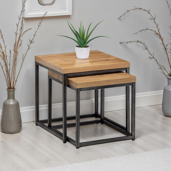 Nest of two wooden tables with metal legs against a gray wall.