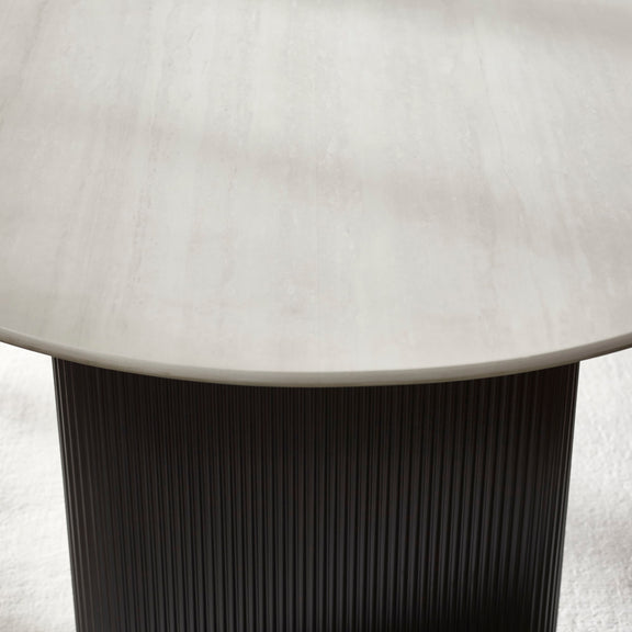 Round table with a light-colored top and dark ribbed base on a neutral background