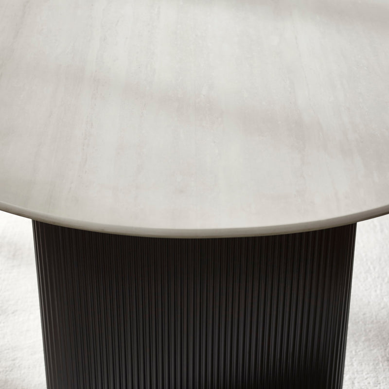 Round table with a light-colored top and dark ribbed base on a neutral background