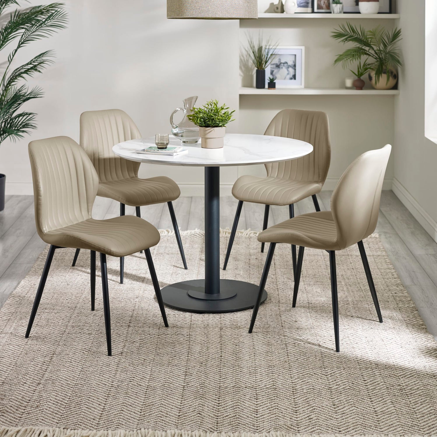 Dining room with a round table and four beige chairs on a textured rug.