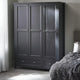 Dark gray wardrobe in a bedroom with a bed and curtains.