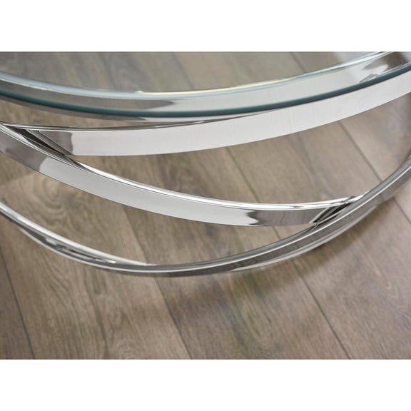 Glass coffee table with chrome metal base on a wooden floor