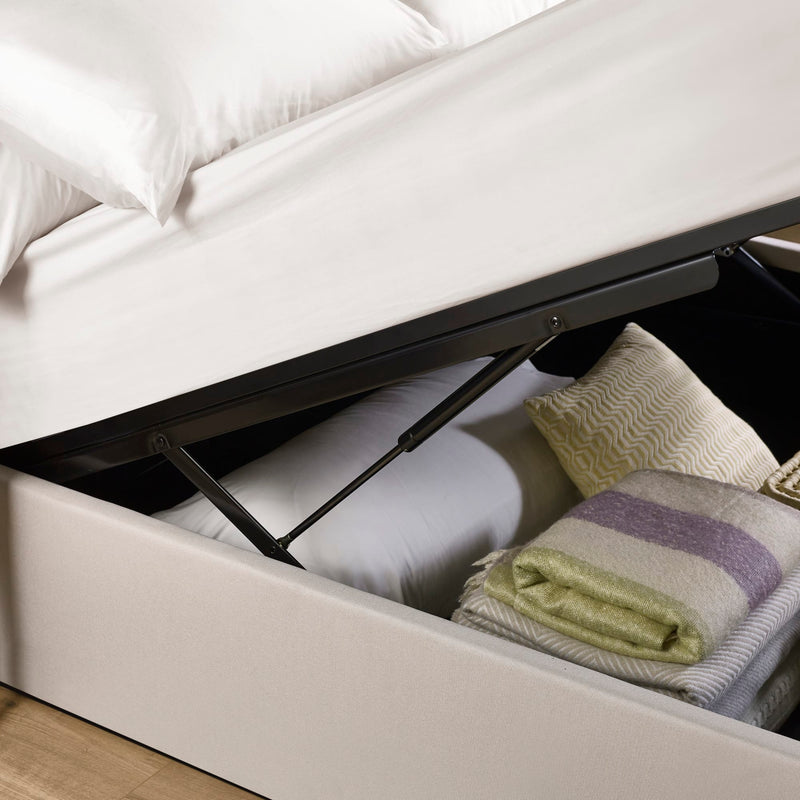 Open storage compartment under a bed with pillows and blankets inside.