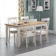 Dining room with a wooden table and white chairs against a green wall.