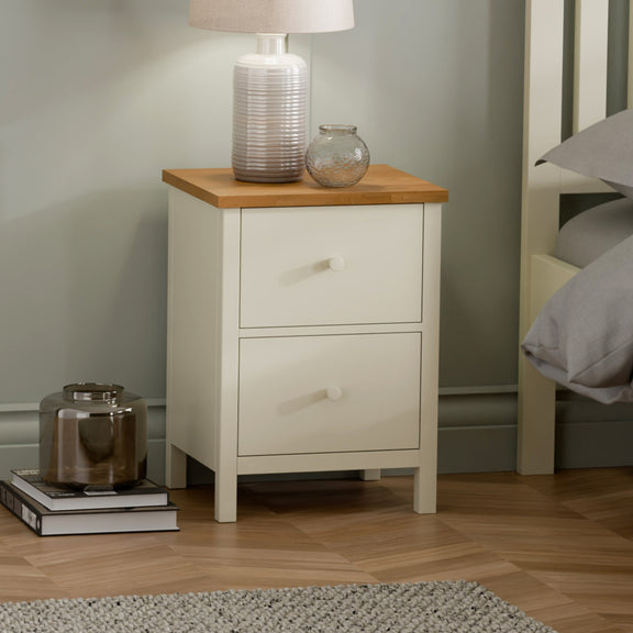 White nightstand with wooden top in a bedroom setting