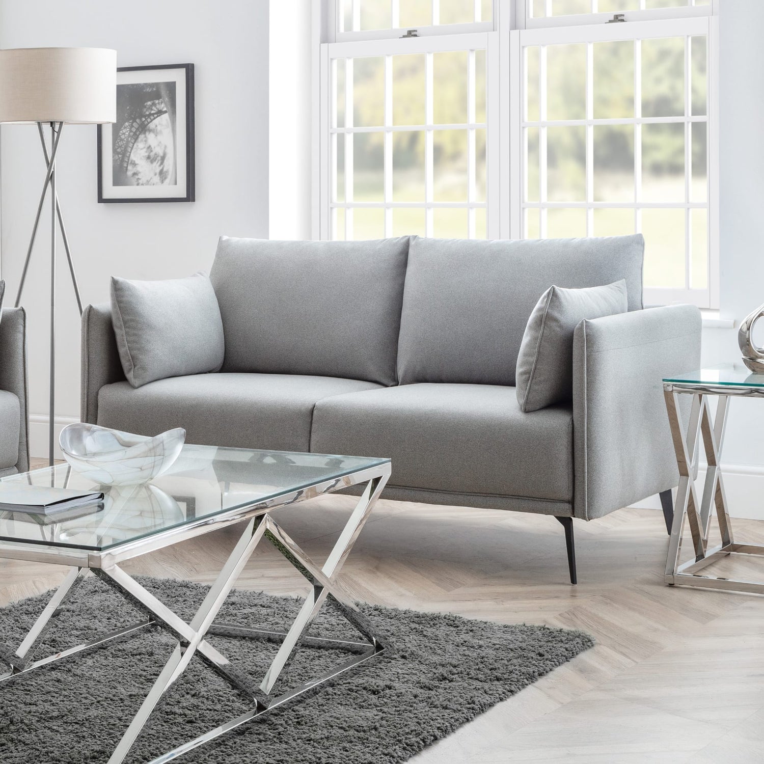 Modern living room with a gray sofa, glass coffee table, and decorative elements.