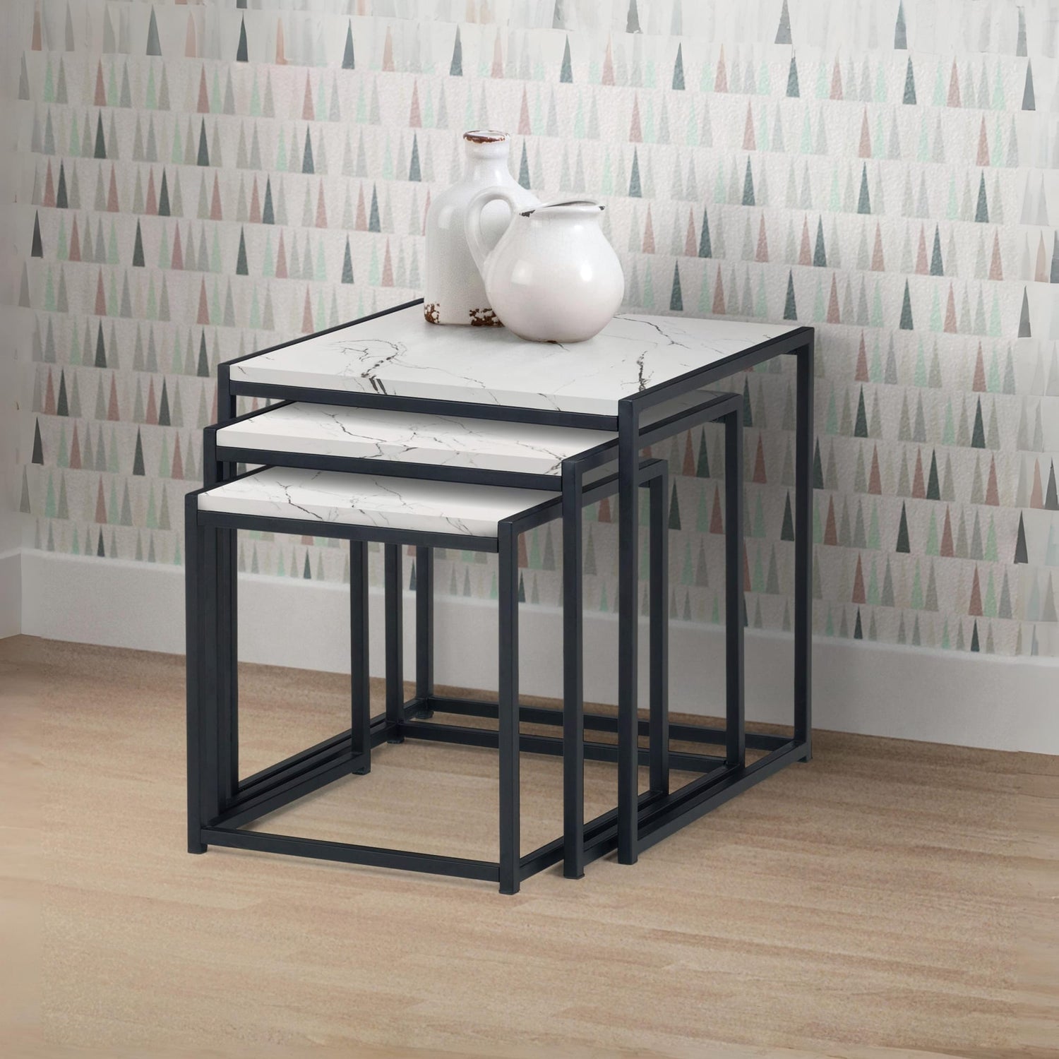 Set of three nesting tables with marble-like tops against a patterned wall.