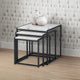 Set of three nesting tables with marble-like tops against a patterned wall.