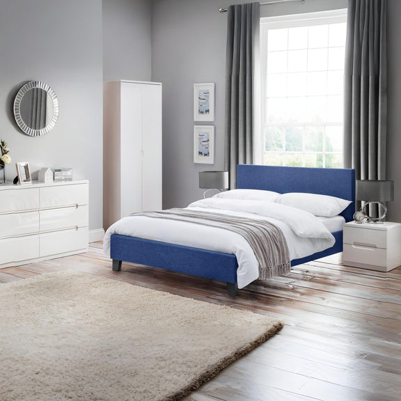 Modern bedroom with a blue bed, white wardrobe, and window with curtains.