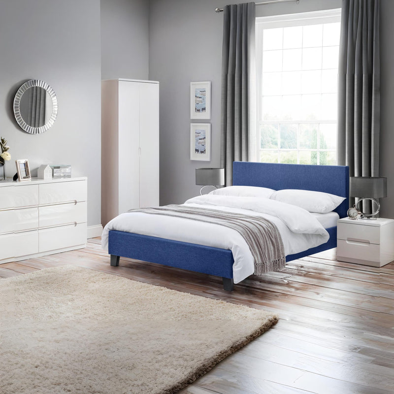 Modern bedroom with a blue bed, white wardrobe, and window with curtains.