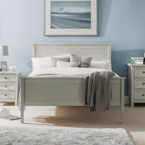 Neatly made bed in a bedroom with light blue walls, nightstands, and a painting.