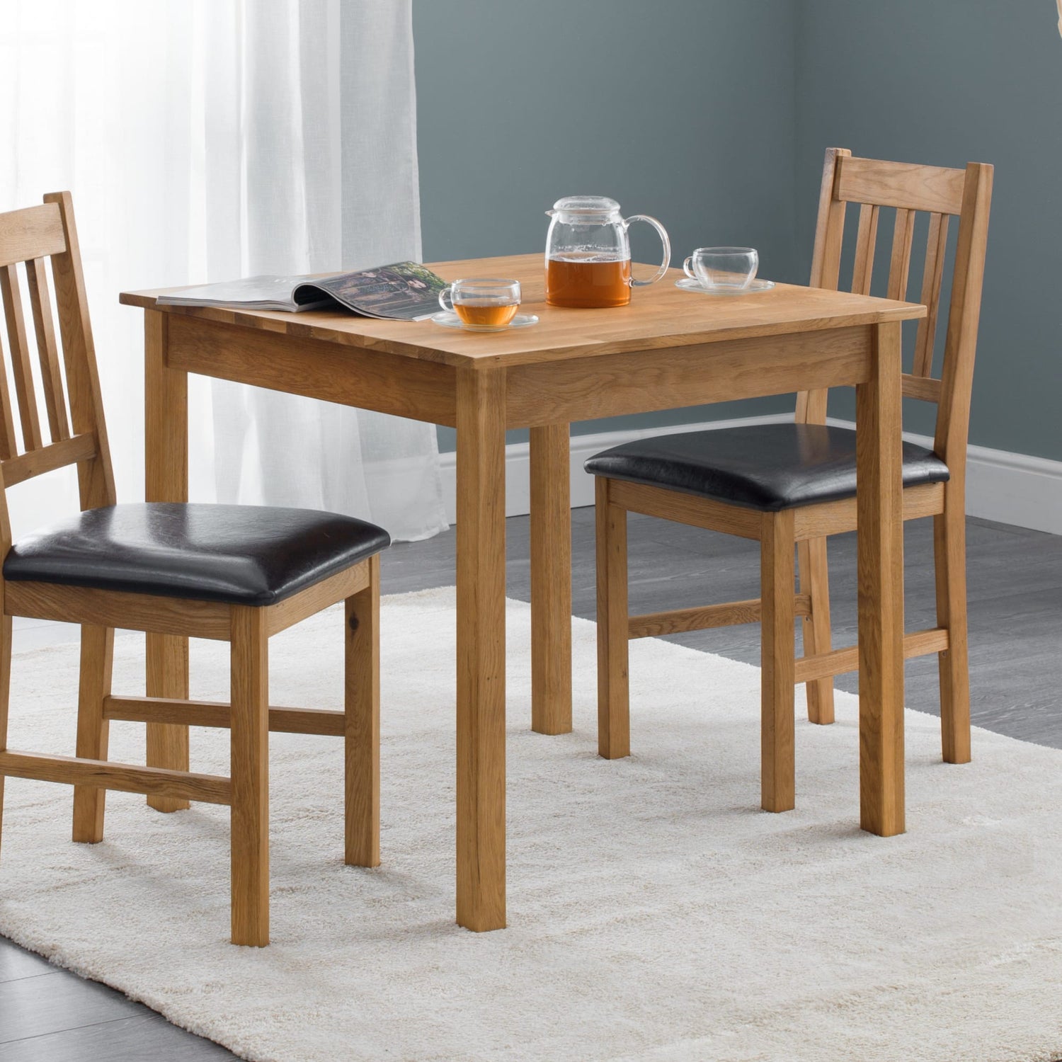 Wooden dining table with chairs and items on a rug