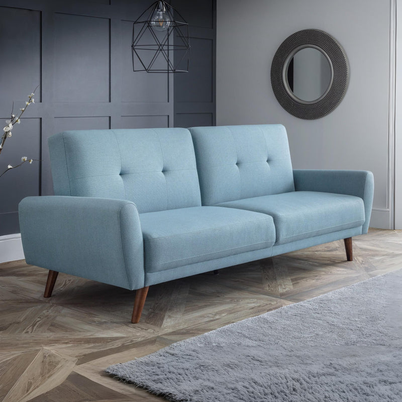 Blue sofa in a room with gray walls and a rug.