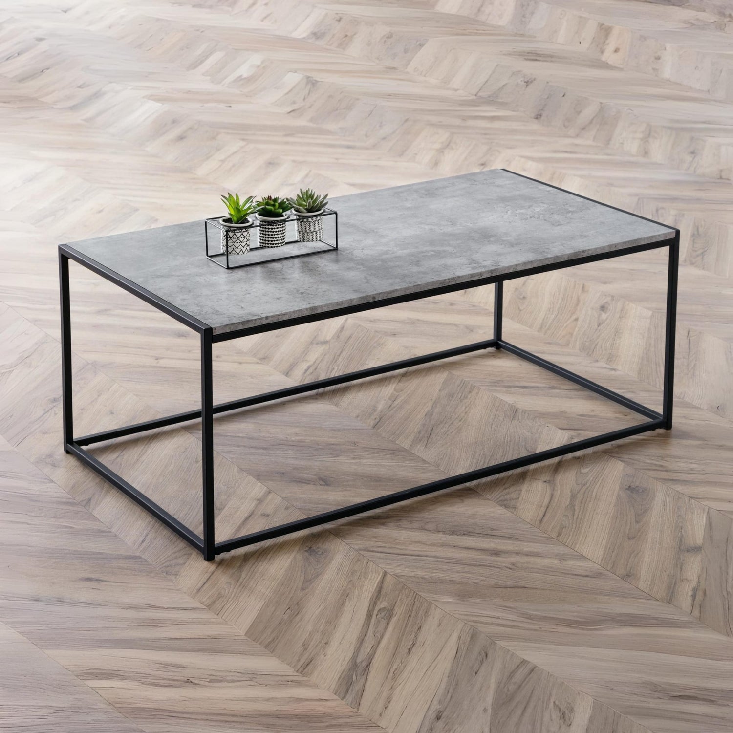Coffee table with a concrete top and black metal frame on a wooden floor.