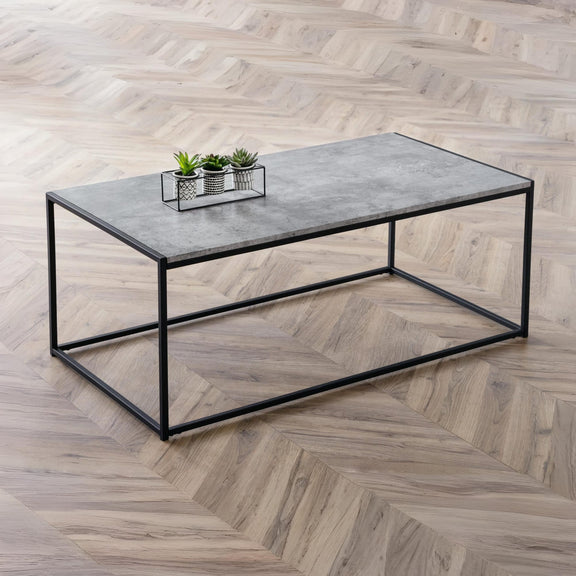 Coffee table with a concrete top and black metal frame on a wooden floor.