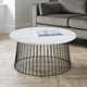 Round coffee table with marble top and black metal base in a living room setting.