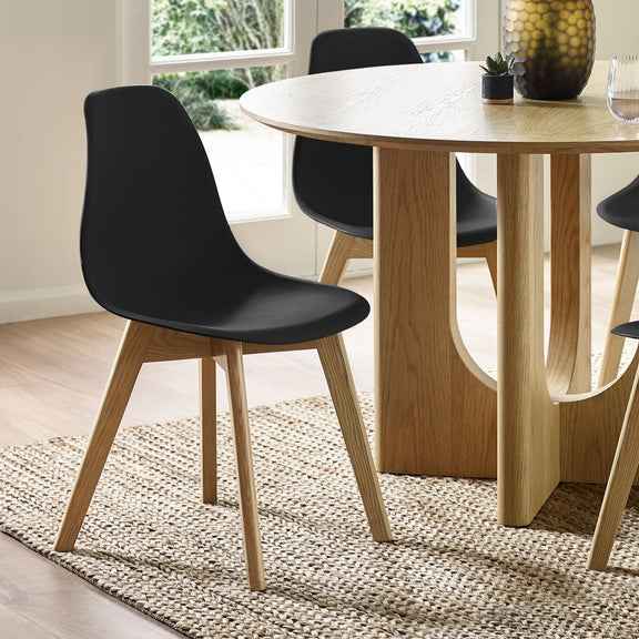Black chairs with wooden legs around a wooden dining table in a bright room.