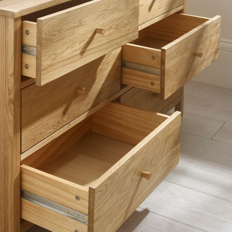 Wooden dresser with open drawers on a light wooden floor.