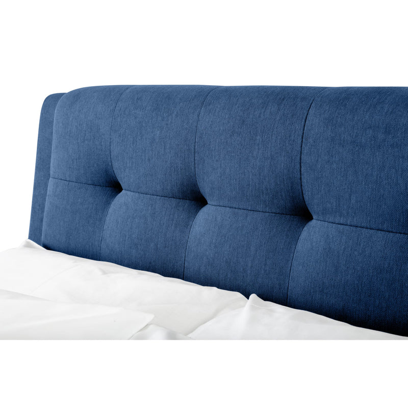 Blue tufted headboard on a bed with white bedding