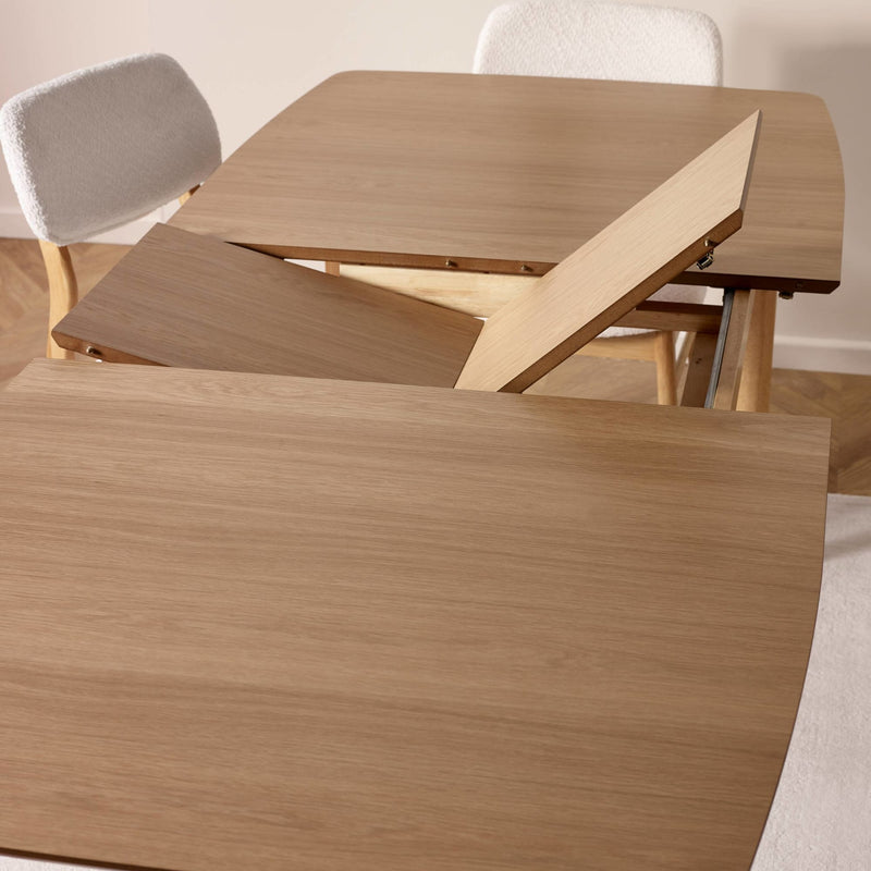 Wooden dining table with a folded leaf extension in a room setting.