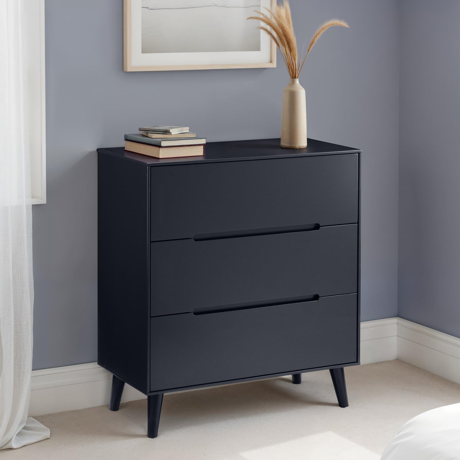 Black dresser with three drawers against a gray wall.