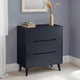 Black dresser with three drawers against a gray wall.