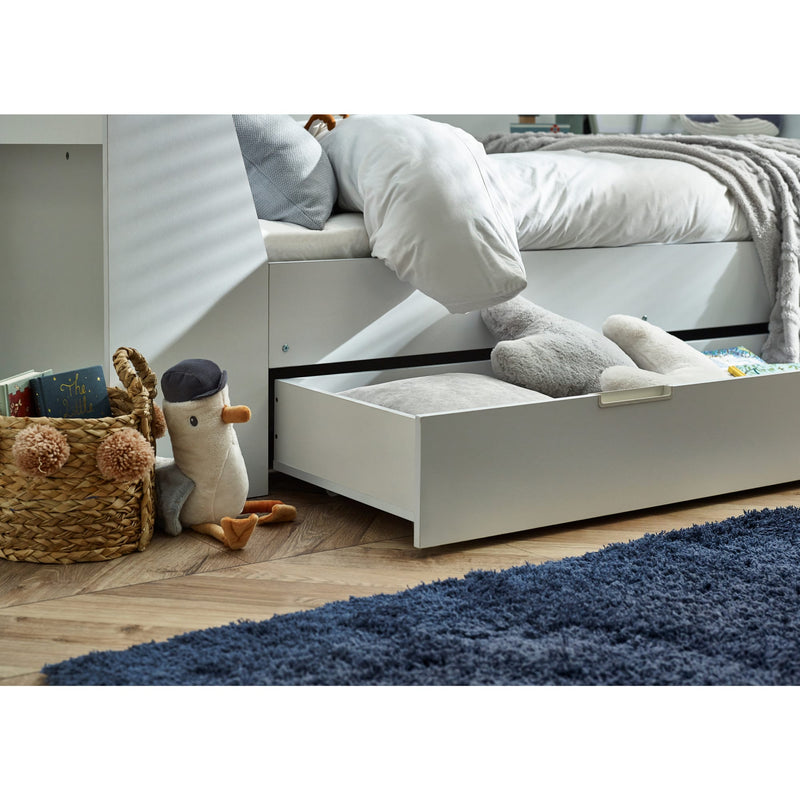 White bed with open drawer revealing toys and storage items in a bedroom setting.