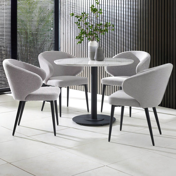Round dining table with four gray chairs in a modern indoor setting.