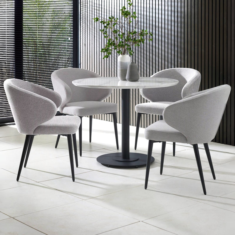 Round dining table with four gray chairs in a modern indoor setting.