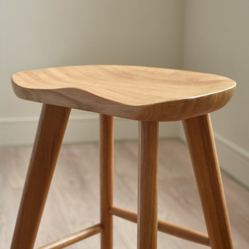 Wooden stool with a light brown finish on a neutral background
