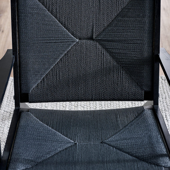 Close-up of a textured black chair with geometric pattern on a light background
