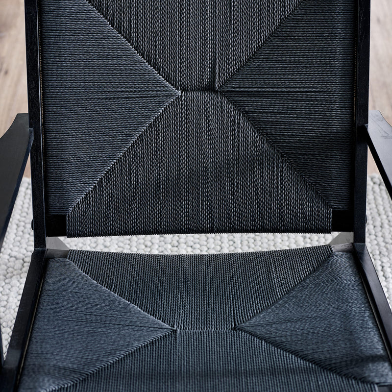 Close-up of a textured black chair with geometric pattern on a light background