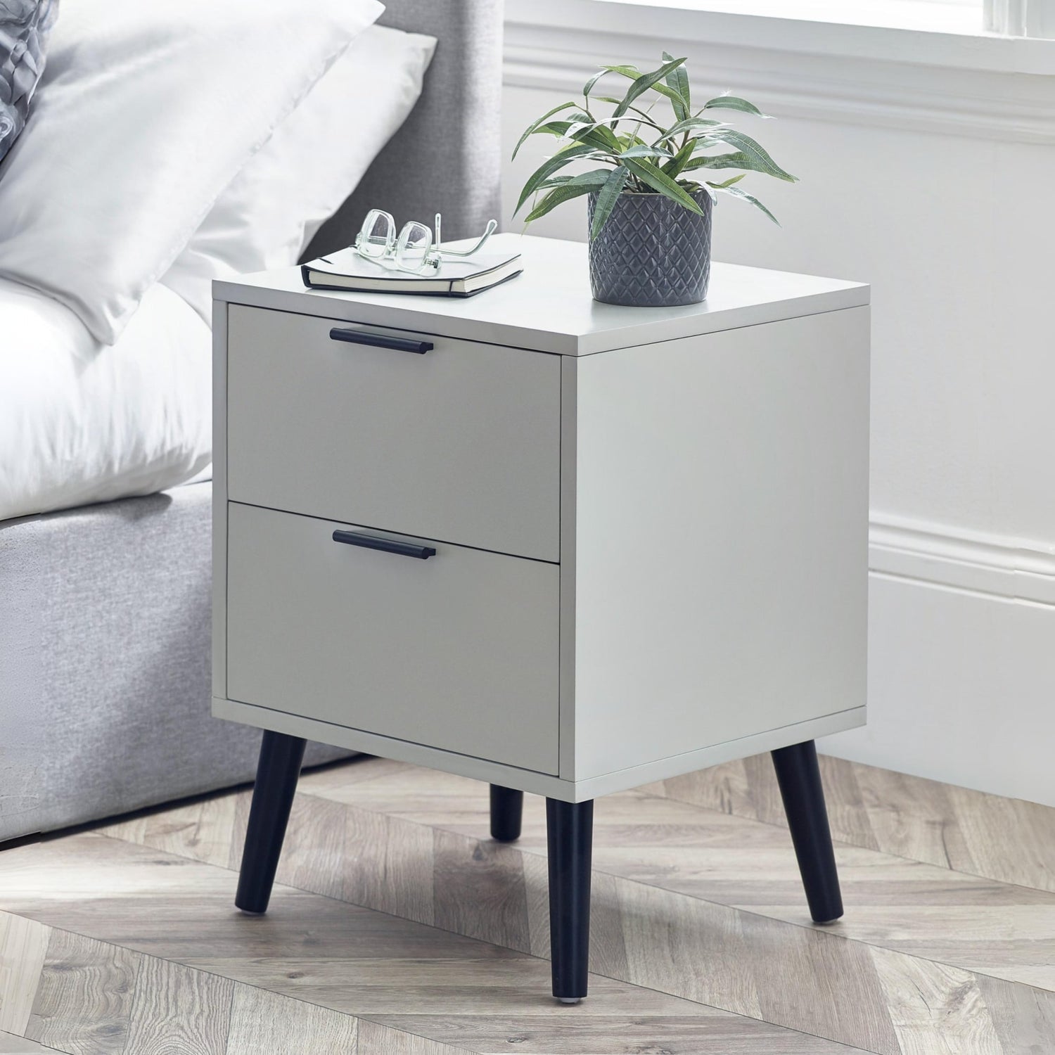 Gray nightstand with two drawers next to a bed in a bedroom setting