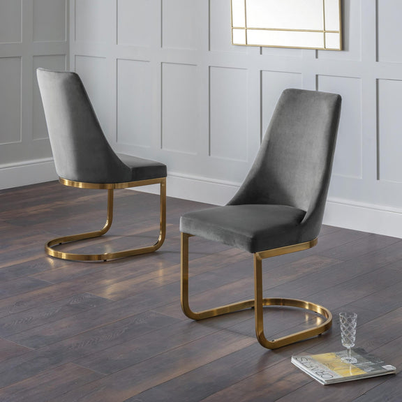 Two gray chairs with gold frames on a wooden floor.