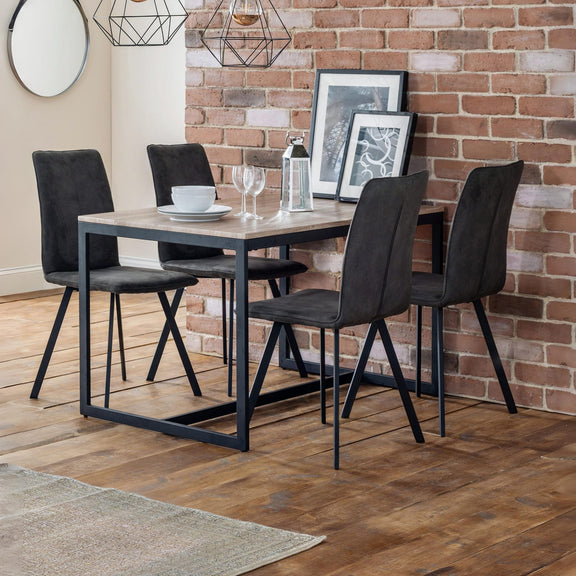Dining table set with four chairs against a brick wall.