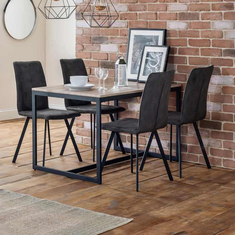 Dining table set with four chairs against a brick wall.