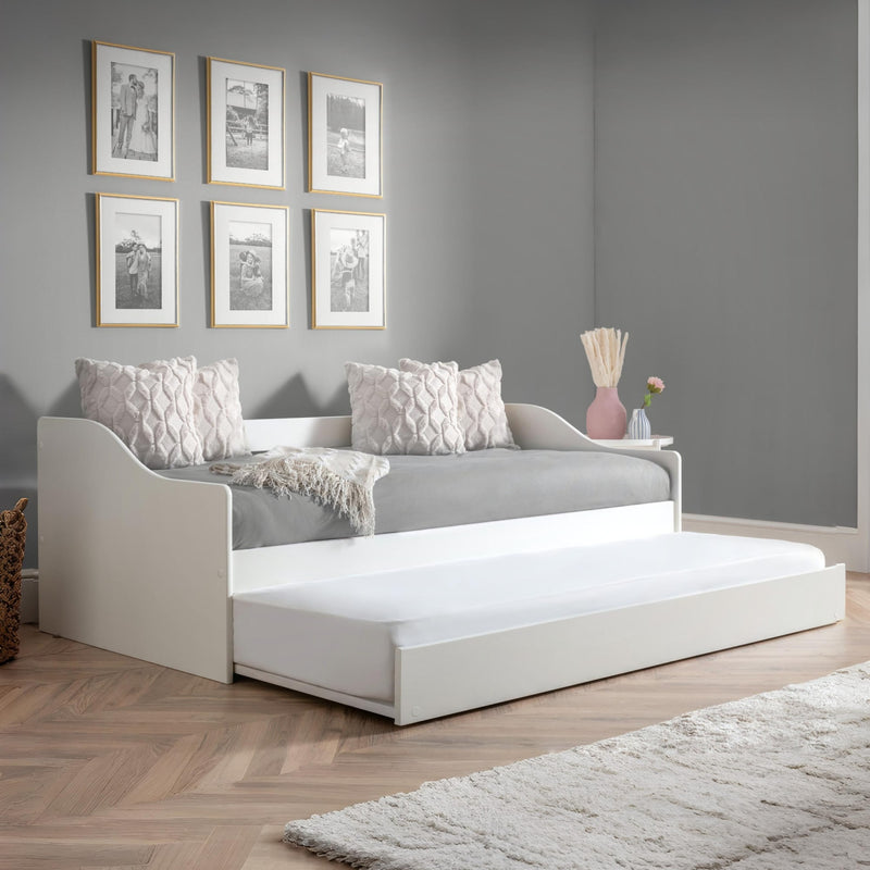 White daybed with pull-out bed in a room with gray walls and wooden flooring.