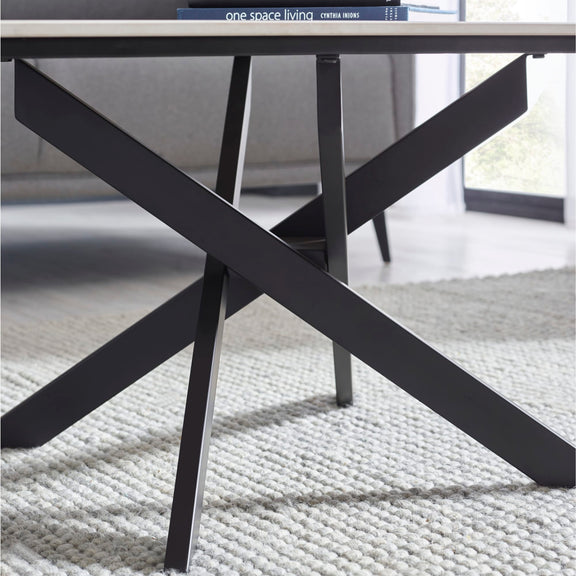 Black metal table with X-shaped legs on a textured surface, with 'one space living' branding visible.