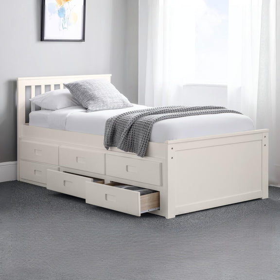 White bed with storage drawers in a room with a gray carpet and a framed picture on the wall.