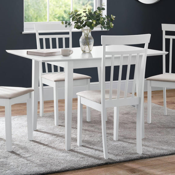 White dining table with chairs in a room with a dark blue wall and window.