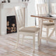 Dining room with wooden table and chairs in front of a fireplace.