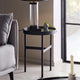 Black side table with a lamp and plant next to a gray sofa in a living room.