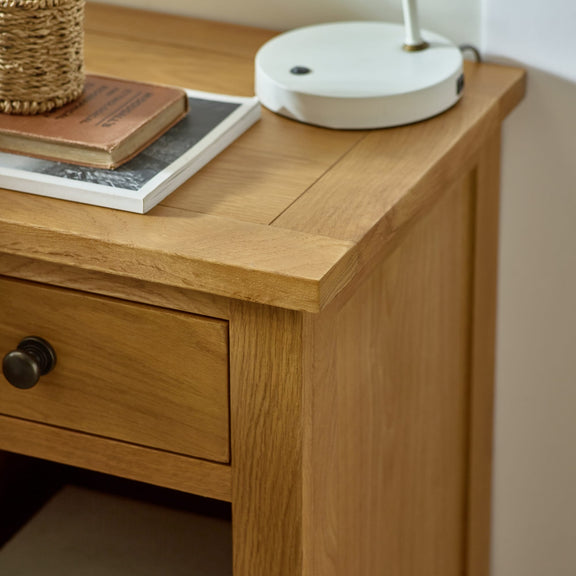 Wooden desk with a lamp and books on top, close-up view.