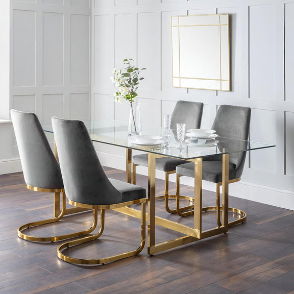Dining room with a glass table and gray chairs on a wooden floor.