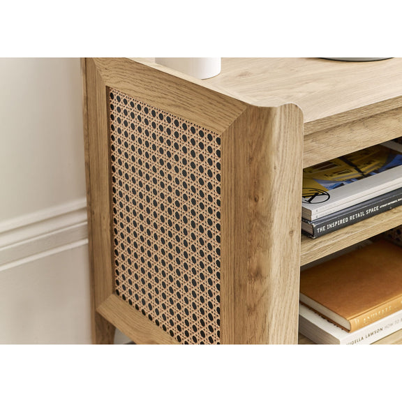 Wooden side table with woven pattern and books on a white wall background