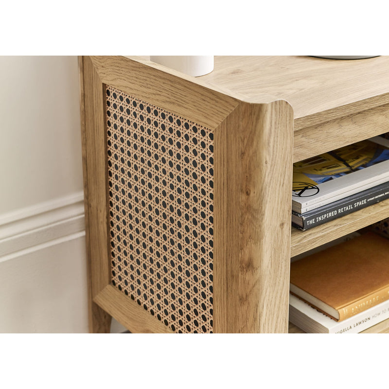 Wooden side table with woven pattern and books on a white wall background