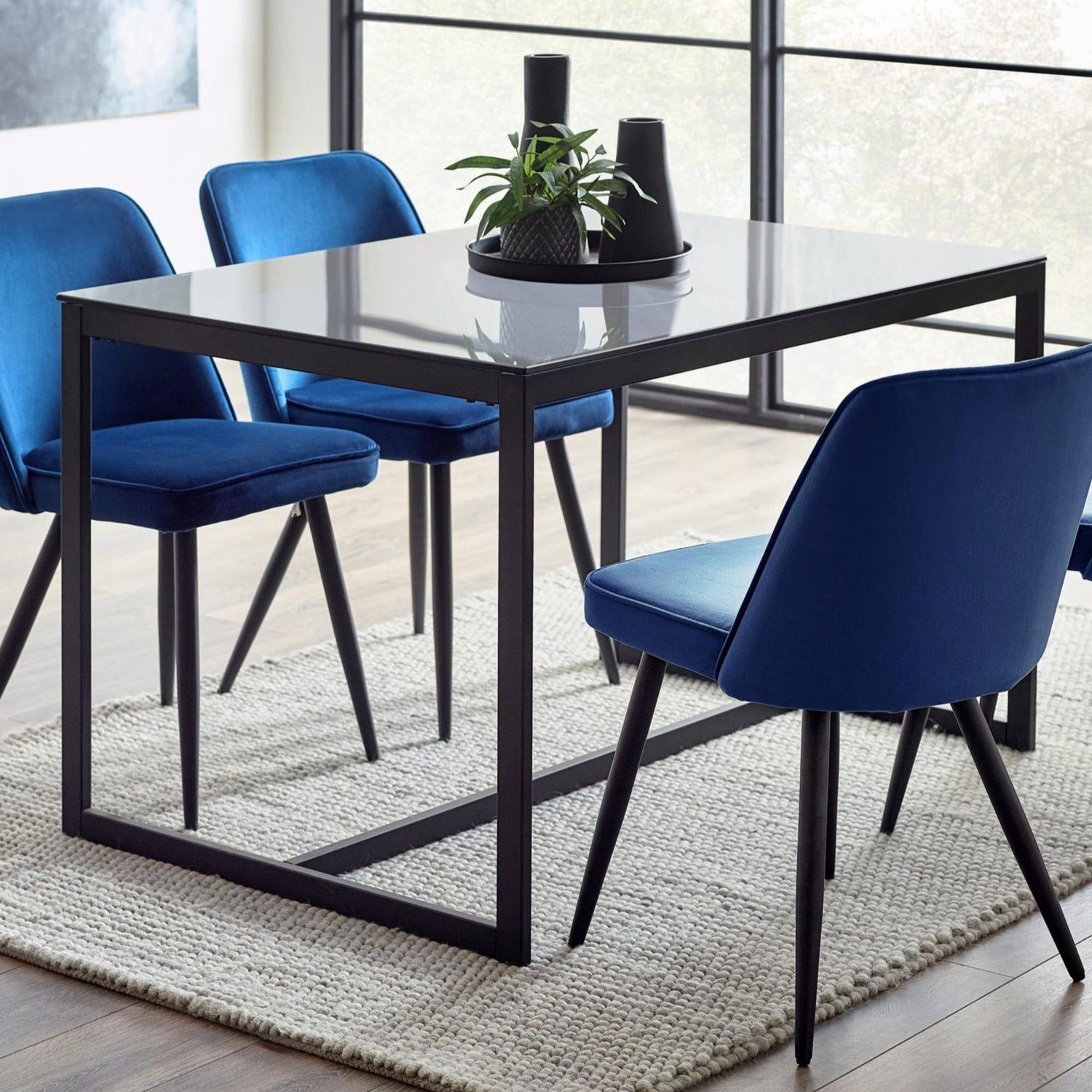 Dining table with four blue chairs in a modern interior setting.