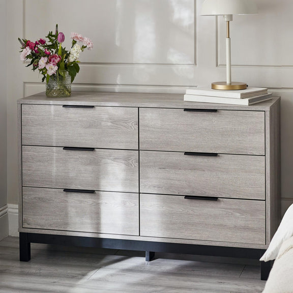 Gray dresser with floral arrangement and books on top in a room setting